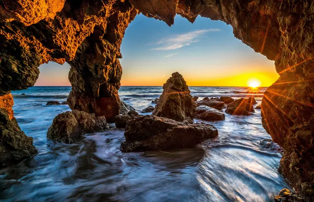 岩や海に反射する太陽の光を長時間露光で撮影した写真