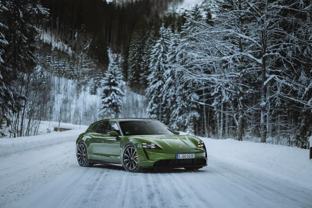 Porsche taycan turbo verde parado en un camino forestal nevado (2022)