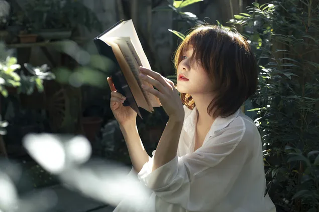 Graži azijietė, skaitanti gražią knygą savo sode 4K ekrano užsklanda