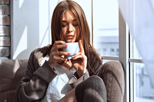 Chica guapa bebiendo café junto a la ventana 4K fondo de pantalla