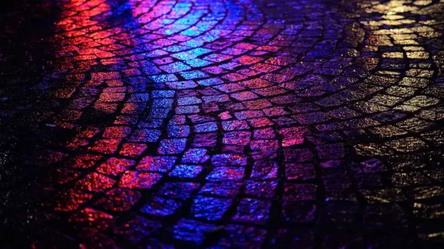 Purple and pink lights reflecting on cobblestones on the street at night