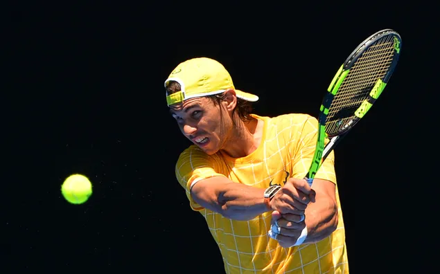 Rafael Nadal begroet tennisbal met omgekeerde slijtage en groen t-shirt en zwarte achtergrond