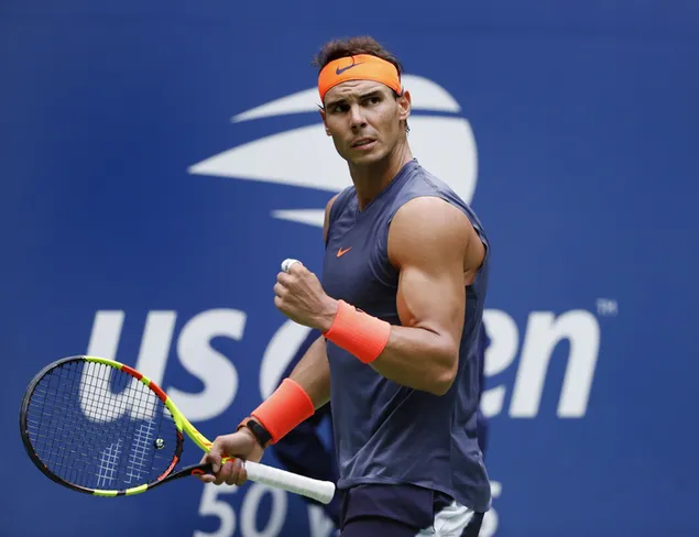 Taustpilt Rafael nadal tähistab punktirõõmu tennisereketiga, mis hoiab tihedalt oranže randmepaelu. 4K