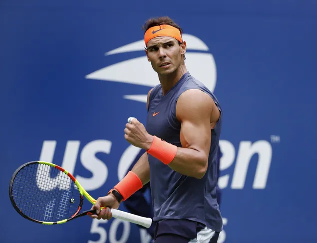 Rafael nadal merayakan kegembiraan poin dengan raket tenis yang memegang gelang oranye dengan erat. unduhan
