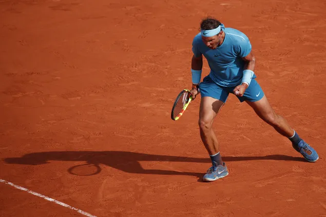 Rafael Nadal feiert seinen Sieg in seinem blauen T-Shirt und steht auf dem Sandfeld herunterladen