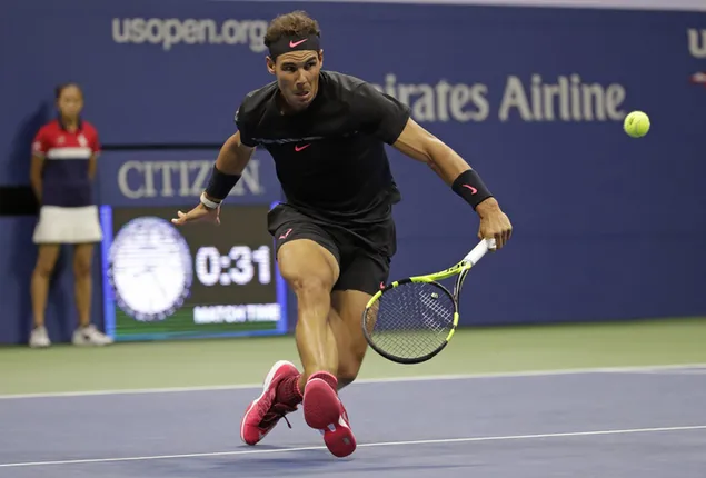 Rafael Nadal läuft in einem schwarzen T-Shirt und roten Schuhen zum Tennisball herunterladen