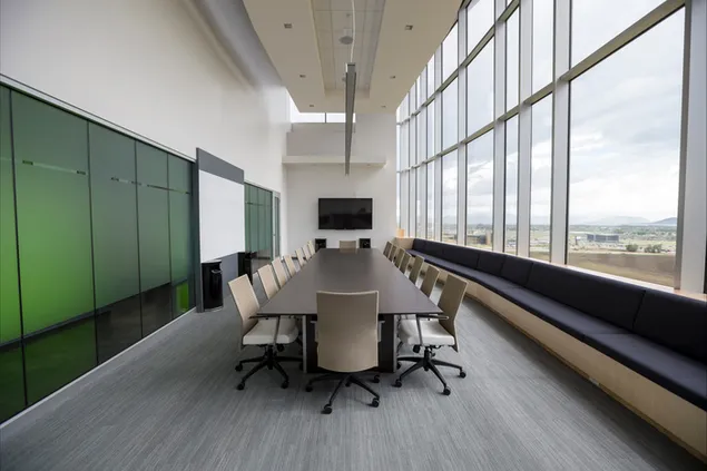 Sala de reuniones rectangular de madera negra con techo alto y grandes ventanales 4K fondo de pantalla