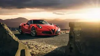 Tapeta Červená Alfa Romeo zaparkovaná na asfaltové silnici vypadá skvěle na slunci 4K
