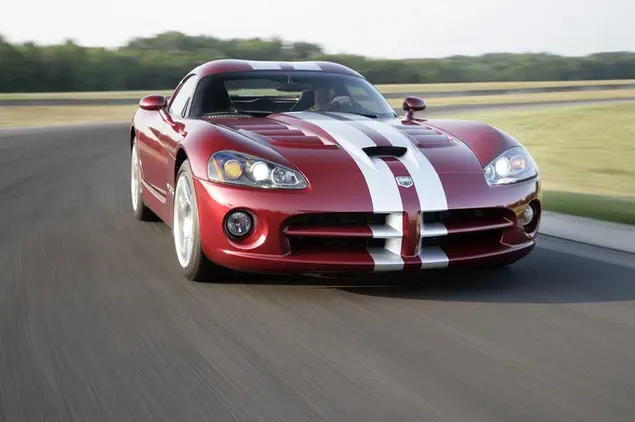 Red and white sports car Dodge Viper SRT 10 on asphalt road in the middle of a field of trees and grass