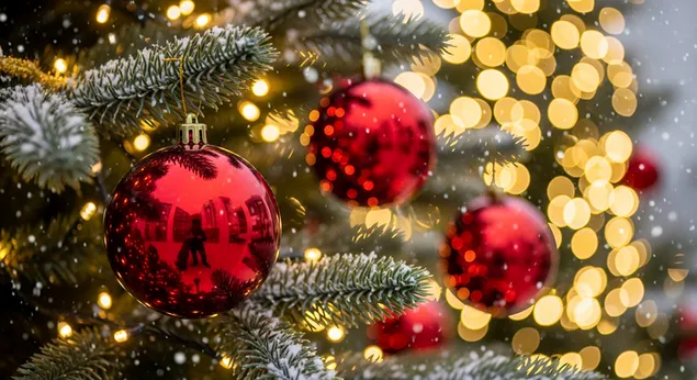 crvene kuglice ukrasene na zimzelenom drvetu prekrivenom snijegom sa svjetlucavim zlatnim svjetlima za bozicne praznike preuzmi