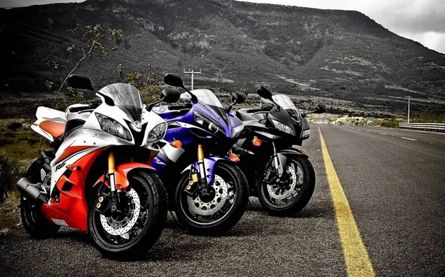 Red blue black and white three motorcycles parked on the asphalt road on the mountain slope 2K wallpaper