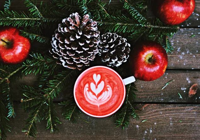 Seni latte kopi merah dan apel merah dengan dekorasi buah pinus