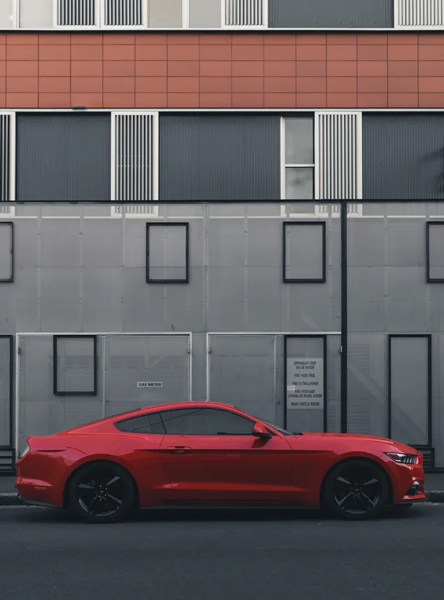 Red Ford Mustang coupe parked beside the building