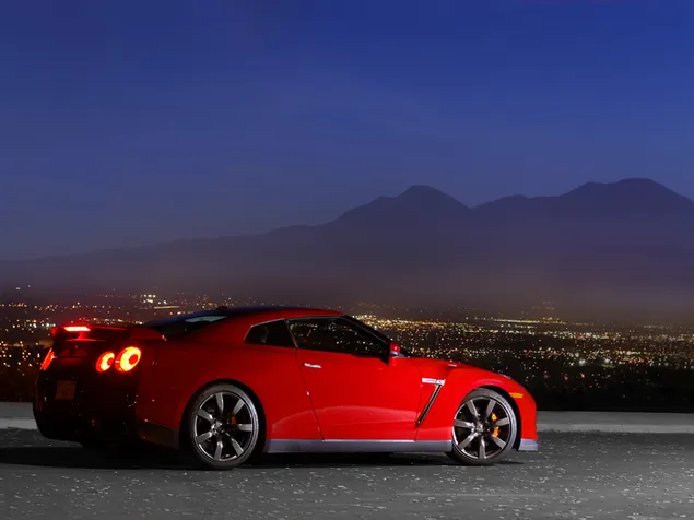 Rode Nissan GT-R geparkeerd in nachtelijk berglandschap download