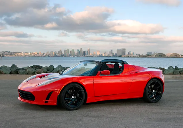 Red open-top tesla roadster on the beach in cloudy weather
