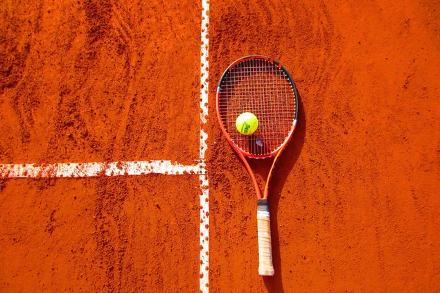 Cancha de tenis roja con raqueta y pelota.