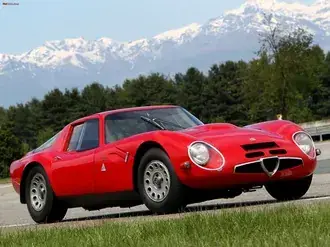 cervena vintage alfa romeo v zasnezenych horach a zelene louce stahnout