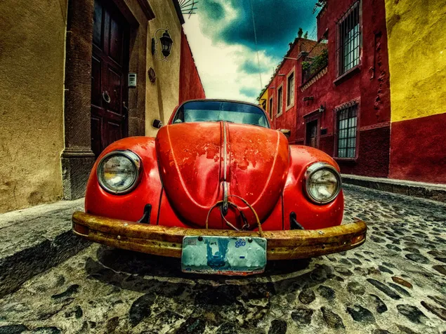 Rotes Volkswagen-Käfer-Coupé parkte an der Straße in der Nähe von Gebäuden 2K Hintergrundbild