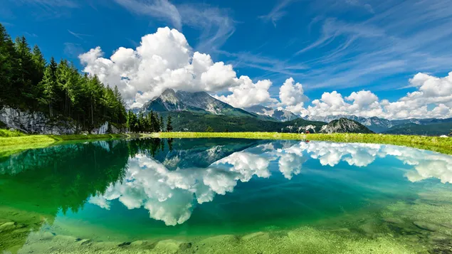 Reflejo de bosques en agua verde clara con nubes blancas reunidas en el pico de la montaña