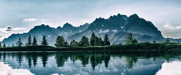 Reflejo de montañas nevadas y colinas y árboles en el agua del lago 8K fondo de pantalla
