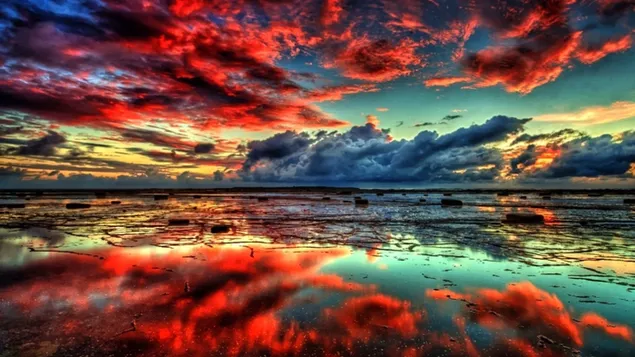 Reflejo de nubes negras, rojas y blancas sobre el agua con piedras