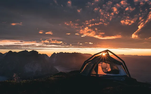 日没時に曇りの景色を望むキャンプテントを通過する日光