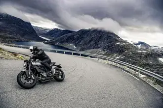 jezdec na sobe cerne rangerske vybaveni s helmou na cernem motocyklu stahnout
