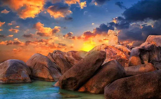 Felsen am Meeresufer im Hinblick auf teilweise Wolken bei Sonnenaufgang 2K Hintergrundbild