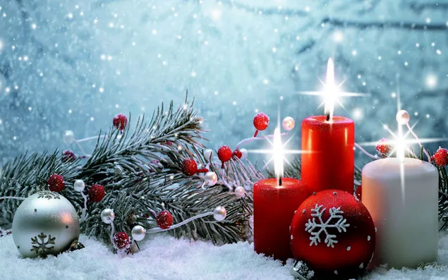 Rode en witte brandende kaarsen en nieuwjaarsversieringen voorbereid op het nieuwe jaar op besneeuwde grond download