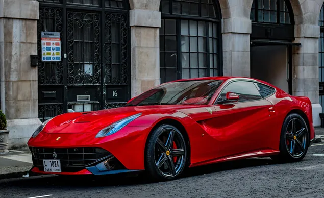 Rode Ferrari F12 berlinetta geparkeerd naast het gebouw