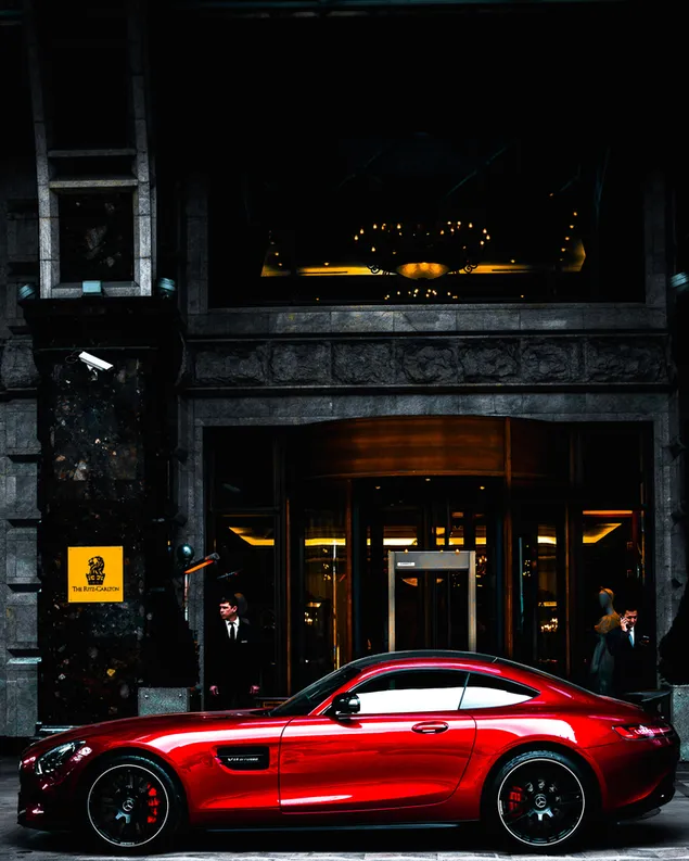 Rode Mercedes geparkeerd voor zwart en grijs gebouw overdag