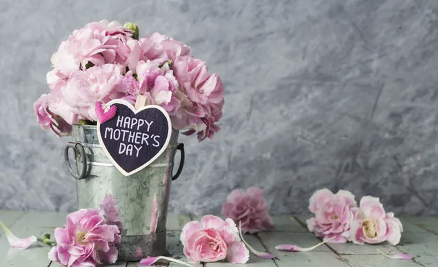 Rosafarbene Blumen in einer Vase für kostbare Mütter und auf dem Holzboden verstreute Blumen