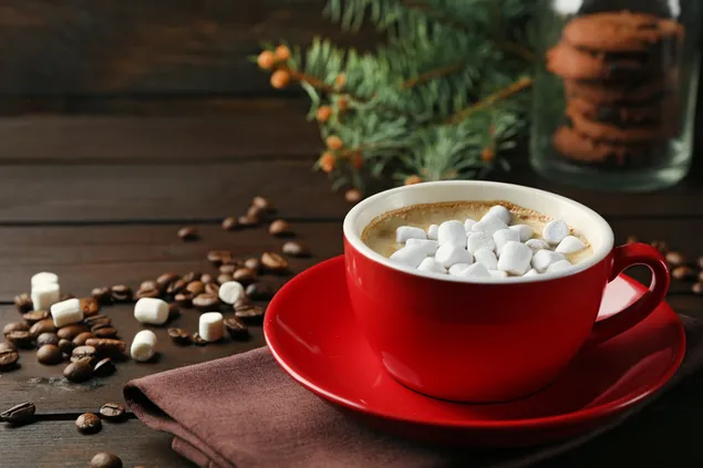 Rote Tasse auf dem hölzernen Hintergrund neben Süßigkeiten und Kaffeeflocken