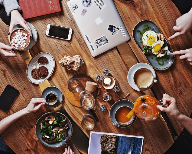 Round table full of variety of foods and drinks with gadgets on the side download