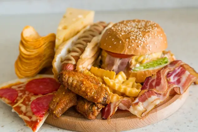 Rundes Tablett voller westlicher Snacks wie Burger, Pizza, Pommes, Sandwich und Brathähnchen