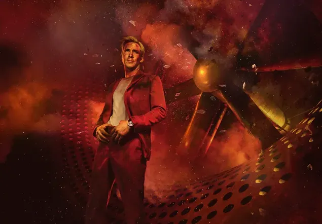 ライアン・ゴズリング、巨大なプロペラの後ろに立っている赤いスーツでセクシー