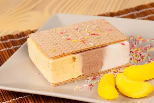 Sándwich de helado con chispas y caramelo amarillo en un plato