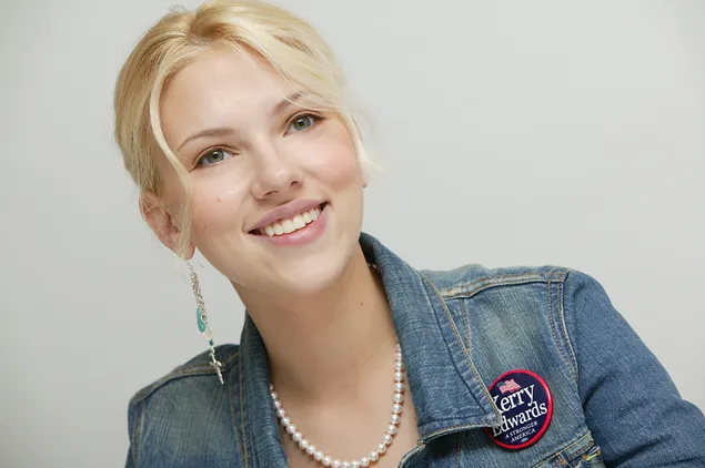 スカーレット・ヨハンソンはブロンドの髪、青い目、赤い唇を持ち、青いデニムジャケットを着て微笑んでいます 4K 壁紙