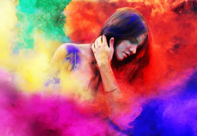 Schöne Frau mit langen Haaren zwischen Farben, die die Ankunft des Frühlings beim farbenfrohen Holi-Festival feiern
