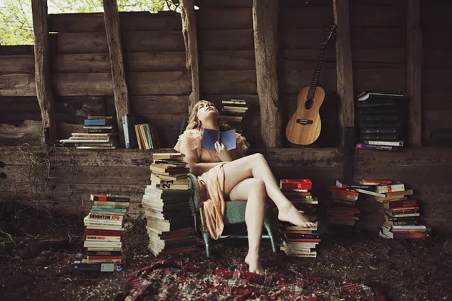 Seksuali šviesiaplaukė knygnešė su knygomis ir gitaros fonu 2K ekrano užsklanda