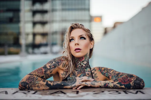 Sexy blonde meid met tatoeages die in het zwembad zwemt