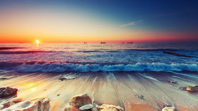 Schiffssilhouetten bei Sonnenuntergang hinter den Wellen