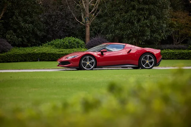 樹木和草地之間道路上紅色法拉利 296 gtb 的側視圖 8K 壁紙