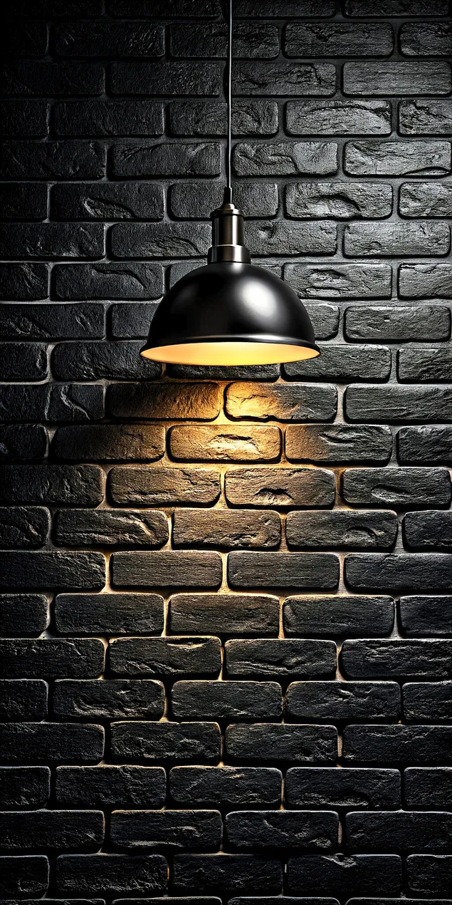 En industriell pendellampa lyser upp en mörk rustik tegelvägg med ett varmt gult sken 2K bakgrund