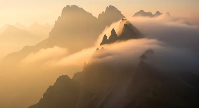 muat turun cahaya pagi yang lembut menapis melalui kabus tebal, perlahan-lahan mendedahkan siluet puncak gunung yang lasak dalam landskap yang tenang dan halus