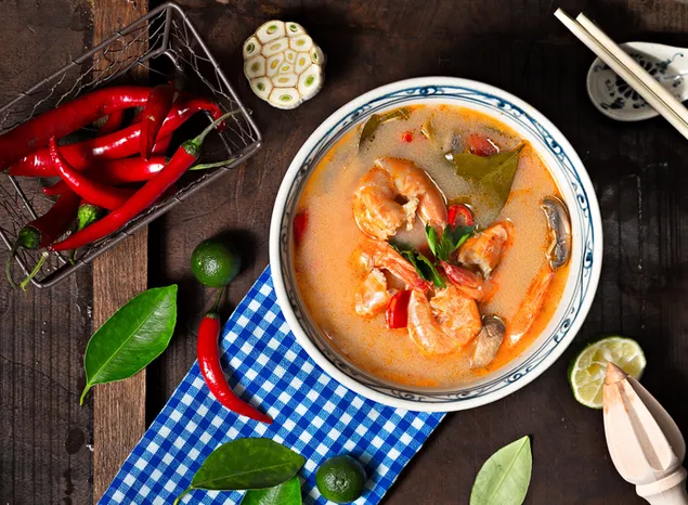 Spicy seafood soup in a bowl with chili pepper and lemon
