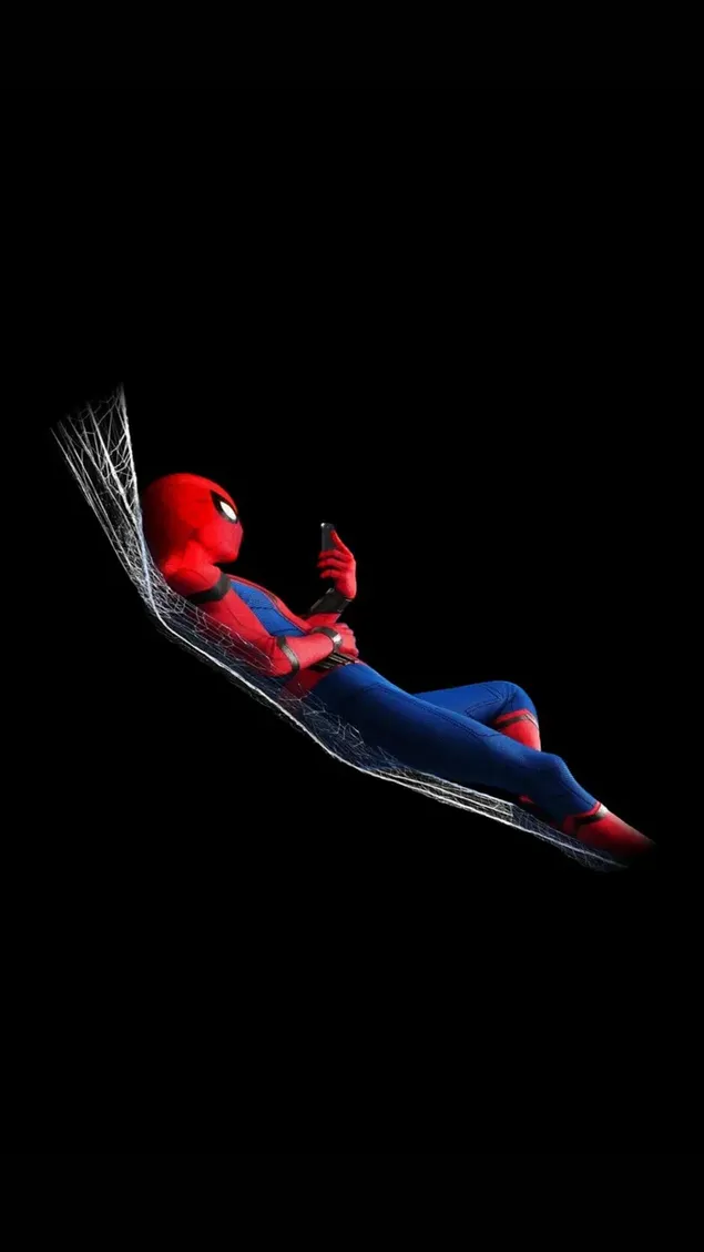 Spiderman playing with phone lying on spider web in front of black background