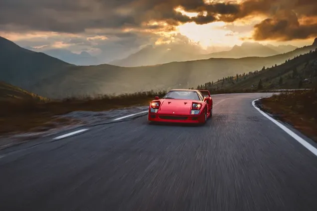 Sportwagen Ferrari F40 rijden op zonovergoten asfalt tussen de wolken achter de bergen download