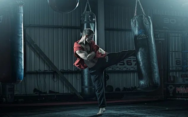 Deportista practicando kickboxing en interiores con un vestido rojo y pantalones negros