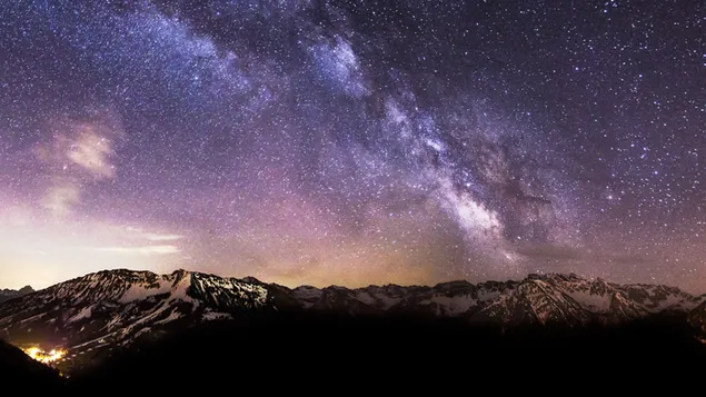 Sterne, die nachts mit Langzeitbelichtungstechnik hinter schneebedeckten Bergen aufgenommen wurden
